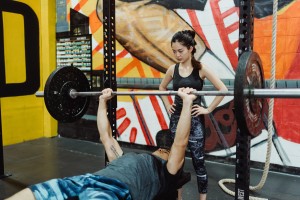 Female trainer supervising man bench pressing