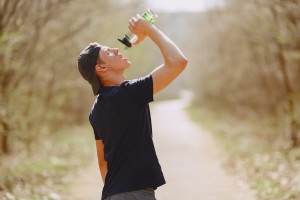Man exercising outside pours water into his mouth